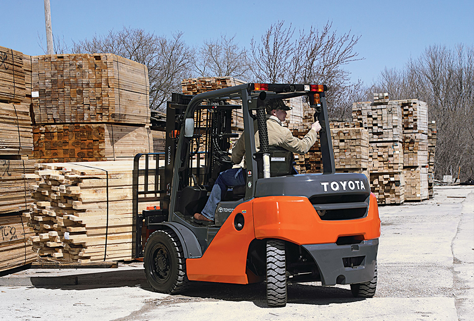 A Toyota forklift driver holding a load of wood planks while is reversing